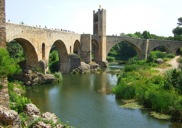 Construido en el siglo XI por el conde Guillem el Gras, ha sido reconstruido en varias ocasiones. Permite cruzar el río Fluviá por sus 105 m de longitud, una torre, de 30 m de altura, da la bienvenida a la ciudad.