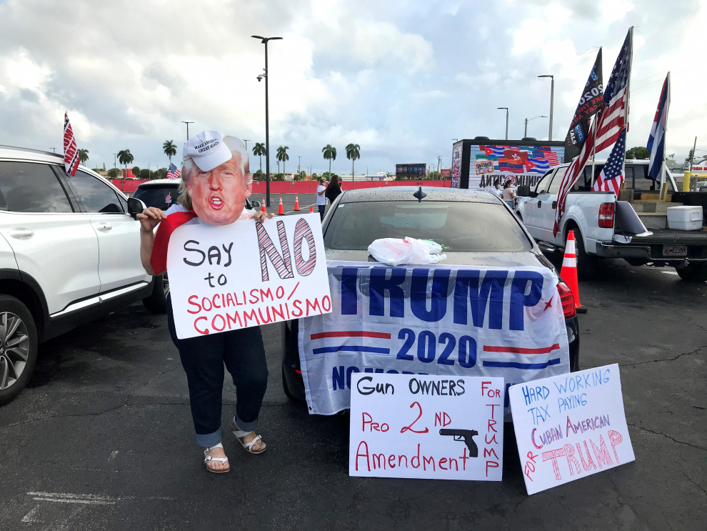 Partidarios del presidente Donald Trump sostienen carteles a favor del candidato en Florida.