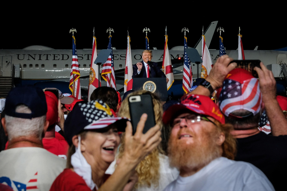 Dos asistentes se toman una fotografía durante el discurso del presidente estadounidense, Donald Trump (C), en un acto de campaña en Pensacola, Florida.