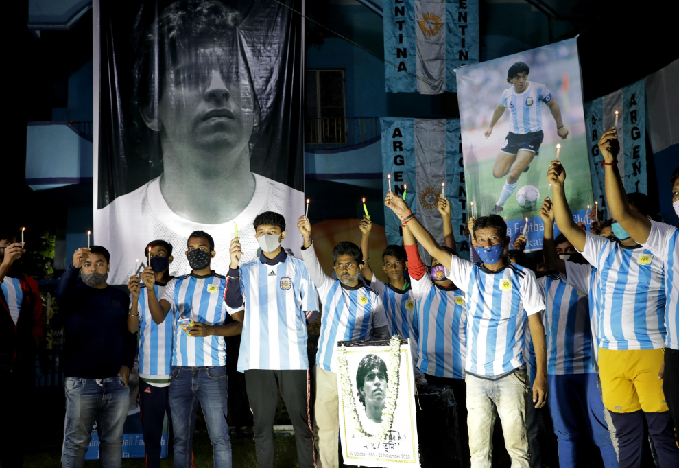 Miembros del club de fans de Maradona sostienen velas con los carteles de Maradona en Calcuta, India.