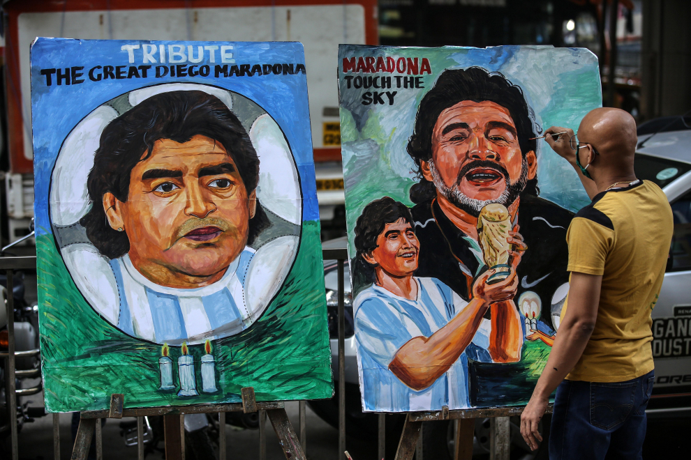El artista indio Sagar Kambli da el toque final a una pintura del legendario futbolista argentino Diego Maradona para rendirle homenaje, frente a su taller en Mumbai, India.