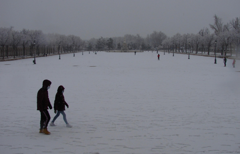 Varios ciudadanos pasean bajo una intensa nevada en la localidad madrileña de Aranjuez.