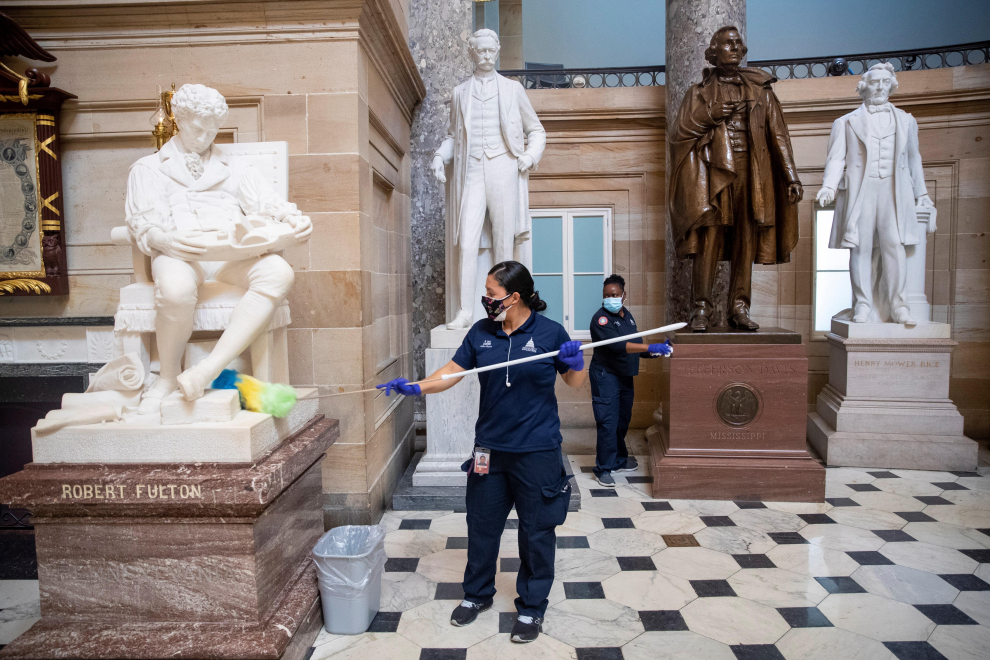 Un equipo de limpieza limpia los pedestales de las estatuas en Statuary Hall dentro del Capitolio de los Estados Unidos.