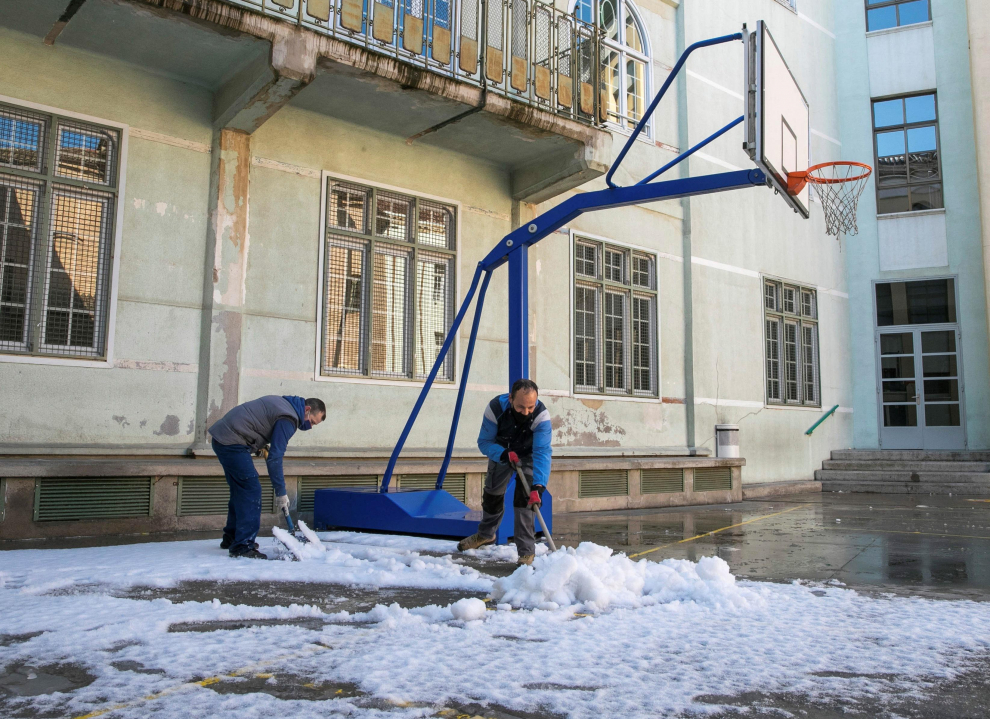 Personal de mantenimiento del Colegio Escuelas Pías de Zaragoza se afana en limpiar la nieve que cubre el patio de recreo del centro este martes.