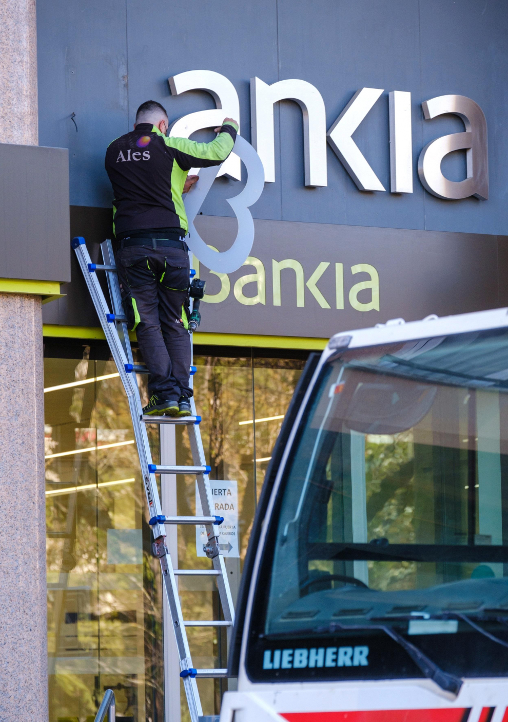Operarios desmontan el rótulo de Bankia de la sede principal del banco en Logroño este sábado tras iniciar CaixaBank su andadura, una vez culminado el proceso legal de fusión con Bankia.
