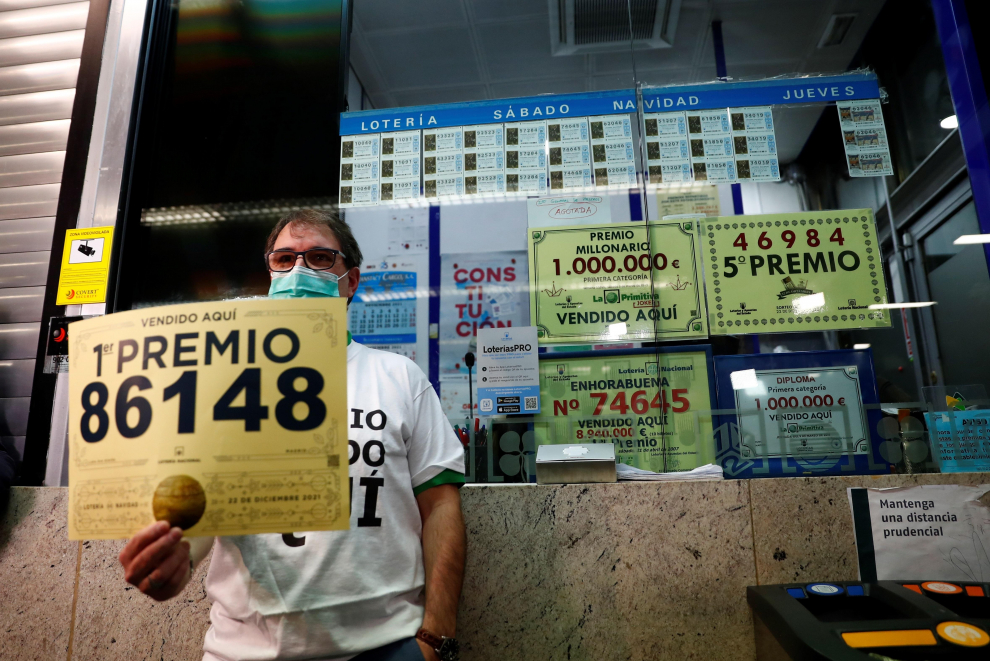 El lotero de la administración donde ha tocado el Gordo del sorteo de la lotería de Navidad muestra el cartel con el número 86.148 agraciado con el primer premio.