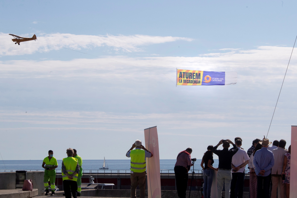 Una avioneta porta una lona donde se lee “Aturem la decadència” (paremos la decadencia) sobre las playas de Barcelona.