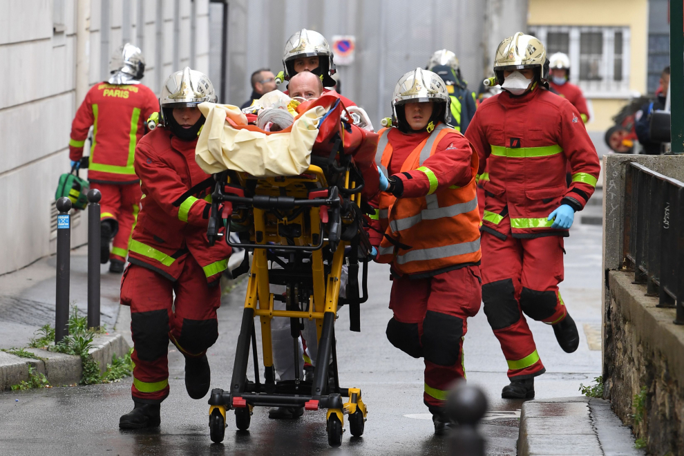 Bomberos franceses empujan una camilla que transporta a una persona herida cerca de las antiguas oficinas de la revista satírica francesa Charlie Hebdo tras un ataque de un hombre con un machete.