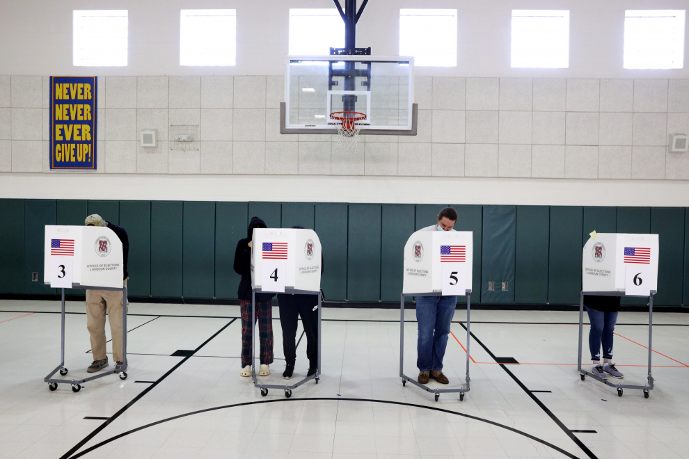 Varias personas votan en cabinas de la Escuela Primaria Emerick en Purcellville, Virginia.