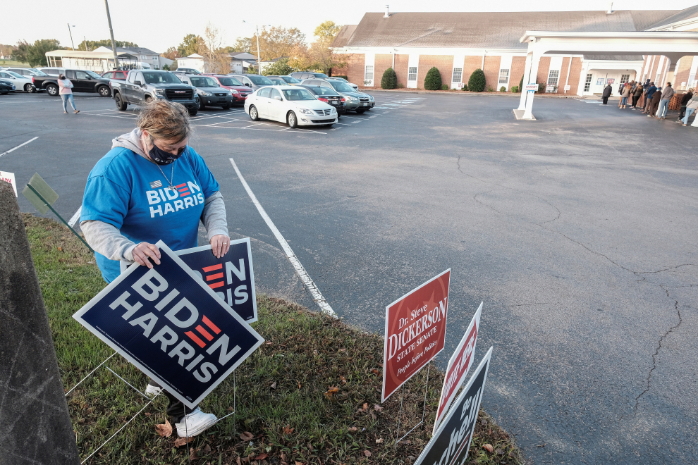 Lee Jones coloca carteles mientras los votantes hacen fila esperando para emitir sus votos en la Iglesia de Cristo Bellevue en Nashville, Tennessee.