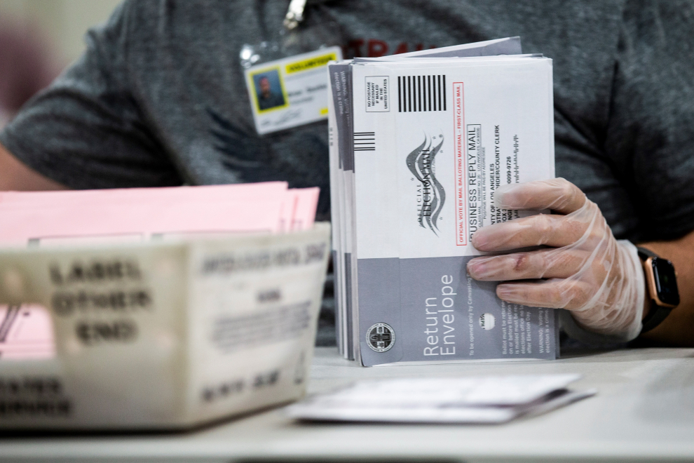 Un trabajador electoral verifica las firmas en los votos por correo en busca de irregularidades en el centro de procesamiento de votos por correo de los registradores del condado de Los Ángeles en Pomona Fairplex en Pomona, California
