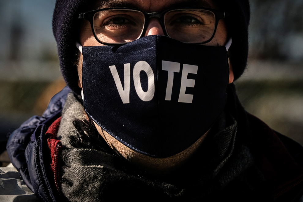 Un votante con una máscara en la que se lee "vota" hace cola en un centro de votación en el Parque Nacional, en Washington, DC.
