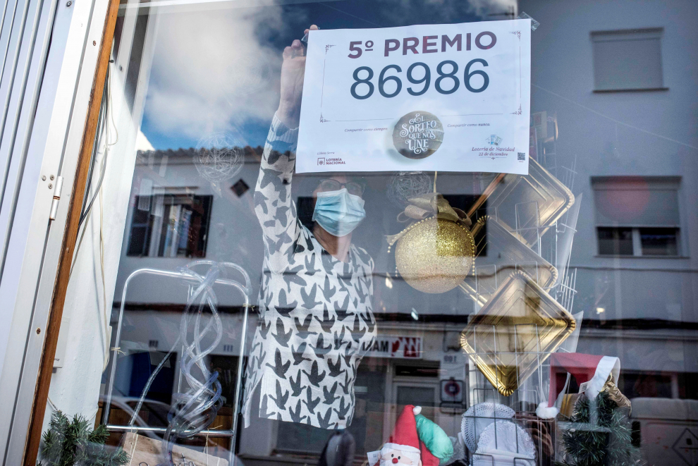 María Isabel Serra, propietaria de la librería y administración Serra, coloca un cartel tras haber vendido décimos del número 86986, uno de los 5º premios del Sorteo Extraordinario de Lotería de Navidad, este martes, en el municipio de Es Castell en Menorca.