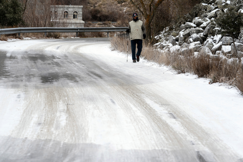 Un hombre pasea por un tramo de la carretera de acceso al embalse de Fuentes Claras con placas de hielo por las bajas temperaturas registradas durante los últimos días en Ávila.