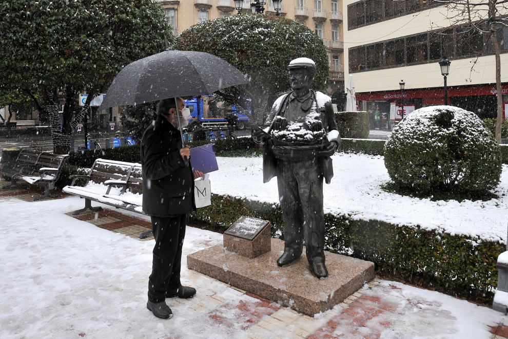 Un ciudadano observa la escultura del Cuchillero durante la nevada en la plaza del Altozano de Albacete.