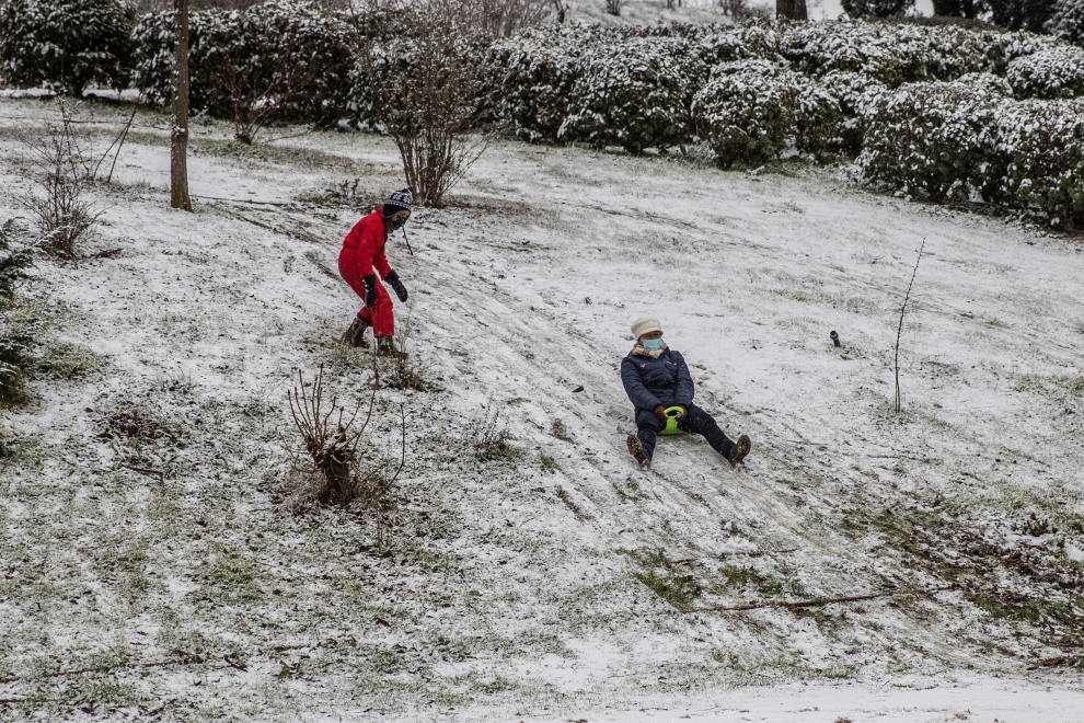 Una mujer se desliza por una pequeña pendiente cubierta de nieve en el Parque de Enrique Tierno Galván durante una copiosa nevada este jueves en la localidad madrileña de Valdemoro.