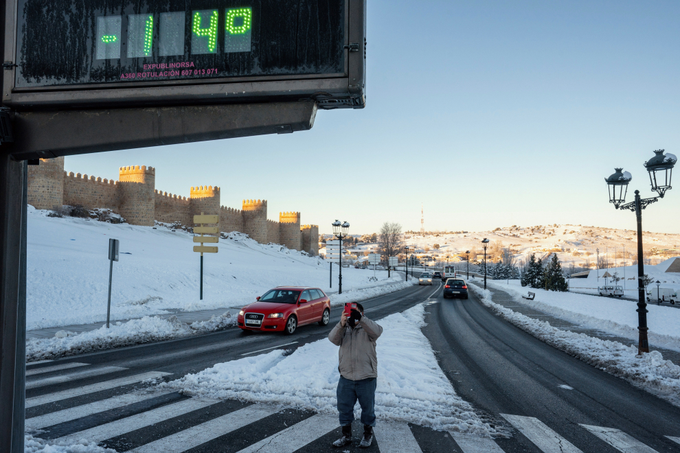 Un hombre toma un fotografía con su móvil de un termómetro que marca 14 grados bajo cero, este martes junto a la muralla de Ávila.