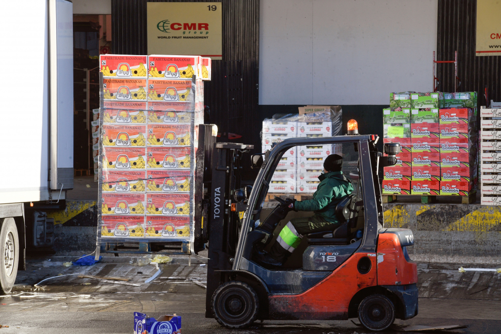Un operario descargar un camión con frutas en los hangares de Mercamadrid que trata de recuperar la actividad.