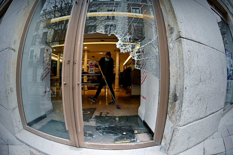Un dependiente recoge cristales en el interior del establecimiento en la zona de la Puerta de Sol tras los disturbios de la noche.