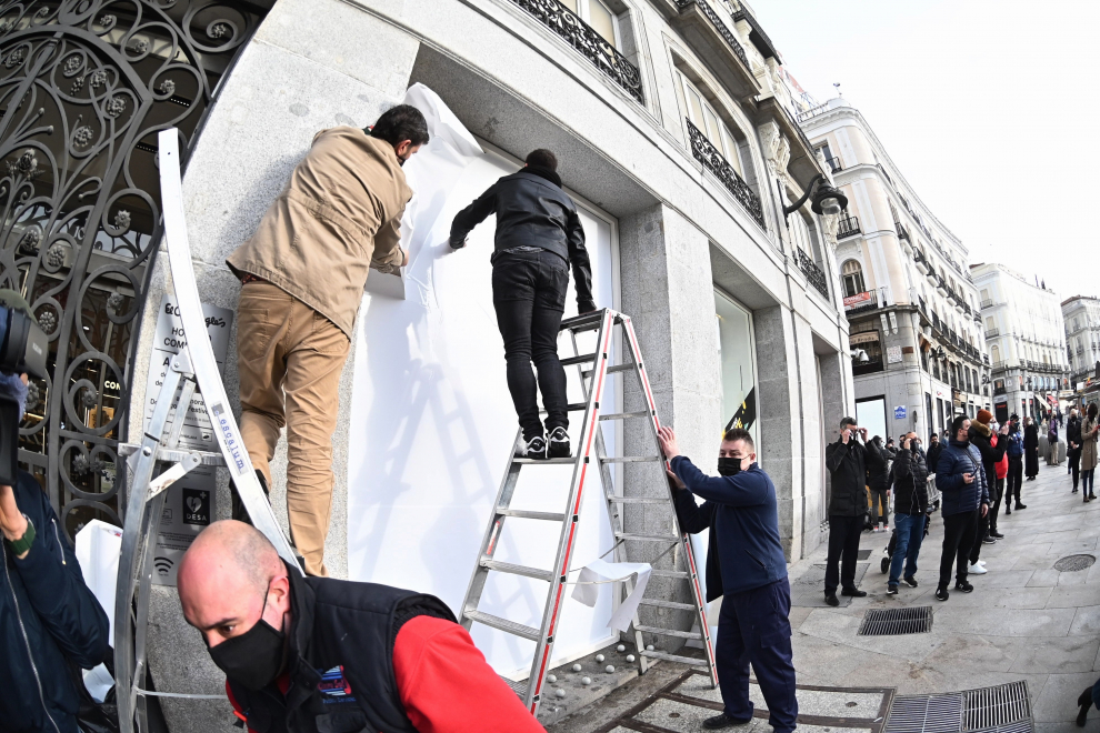Trabajadores arreglan el escaparate de una tienda en la Puerta de Sol tras los disturbios de la noche del miércoles