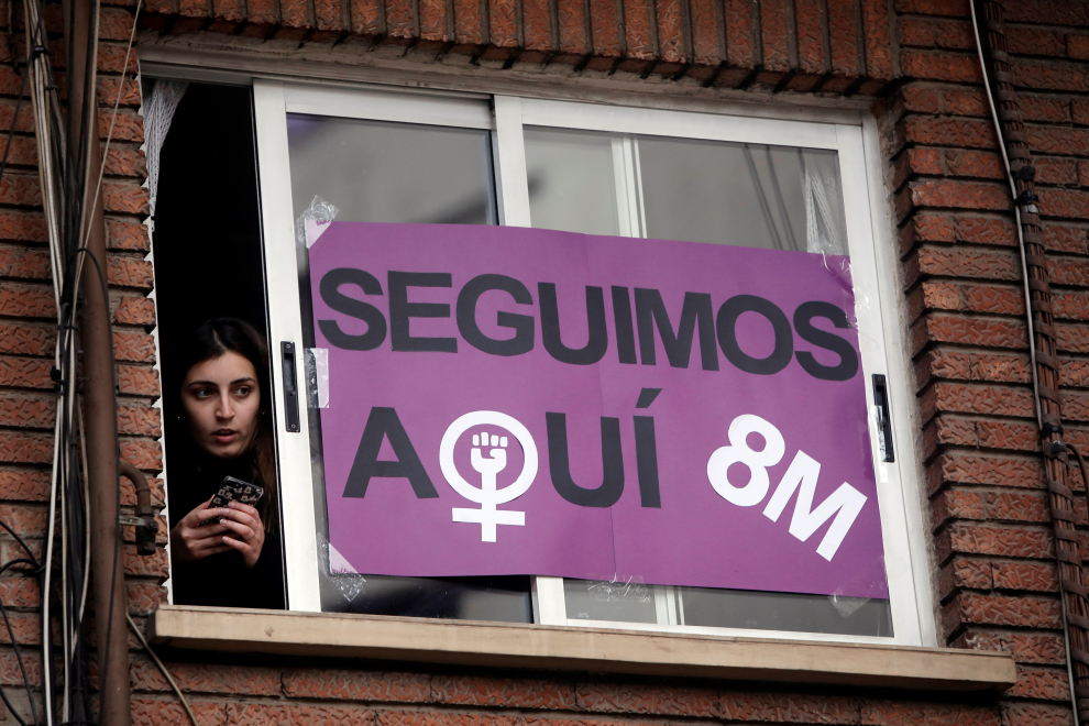 Una mujer se asoma a la ventana engalanada, en Valencia, con motivo del Día de la Mujer en el que los actos reivindicativos, concentraciones y movilizaciones están marcados por las restricciones dictadas para hacer frente a la pandemia de coronavirus.