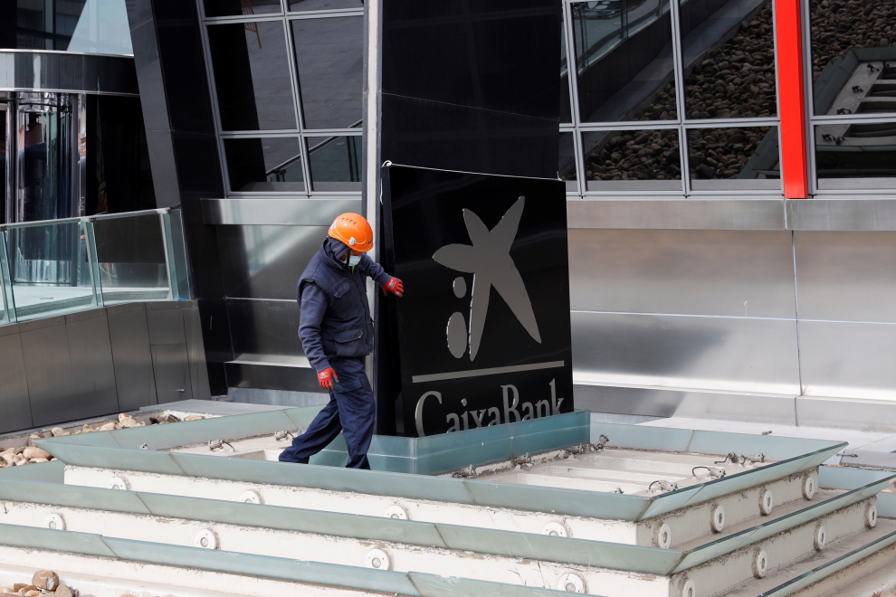 Operarios sustituyen este sábado uno de los rótulos de Bankia por otro de la nueva CaixaBank en las torres Kio de Madrid, sede operativa del banco nacionalizado estos últimos años.