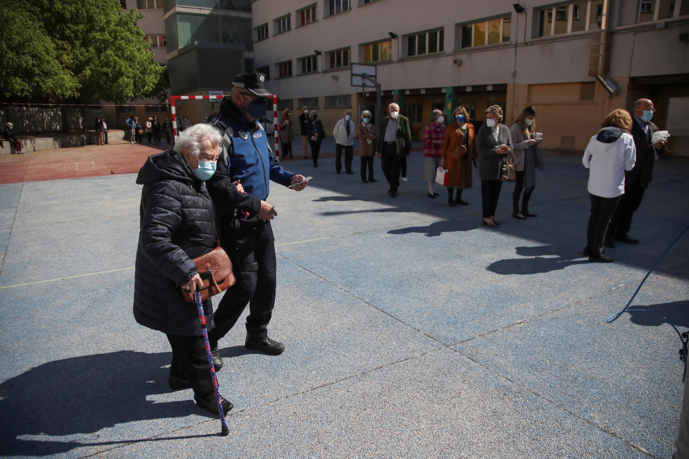 Una anciana recibe ayuda para acceder a su colegio electoral de Madrid en las elecciones autonómicas que este martes vive la Comunidad.