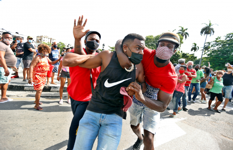 Dos hombres detienen a un participante de la marcha en las calles de La Habana.