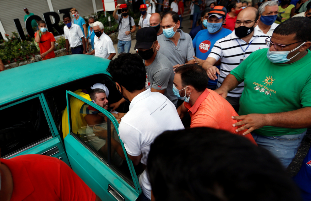 Varios efectivos arrastras hasta un coche a uno de los manifestantes en La Habana.