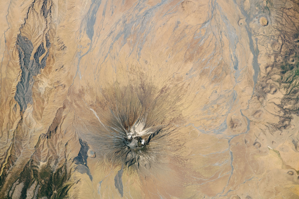 Ol Doinyo Lengai, conocido por el pueblo masai como la “ Montaña de Dios ”, es un estratovolcán en Tanzania con características geológicas únicas. La fotografía capta el volcán simétrico, así como los cañones y los flujos de lava formados por la actividad volcánica previa. La cima está coronada por un cono de ceniza de color claro y un cráter. Tomada el 6 de octubre de 2020