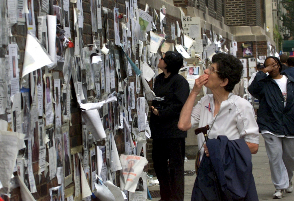 Una mujer mira fotografías y mensajes en busca de personas desaparecidas en una pared en Manhattan, los rescatistas siguen buscando a más de 6.000 personas en los escombros del World Trade Center.