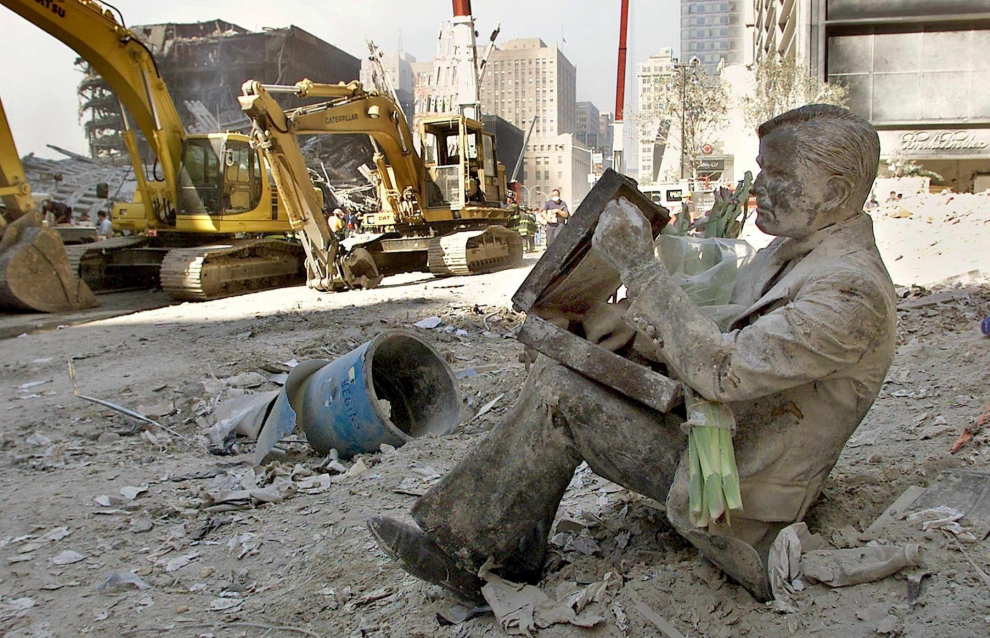 Una estatua de bronce, de un hombre con su maletín, aparece cubierta de polvo en los escombros del World Trade Center.