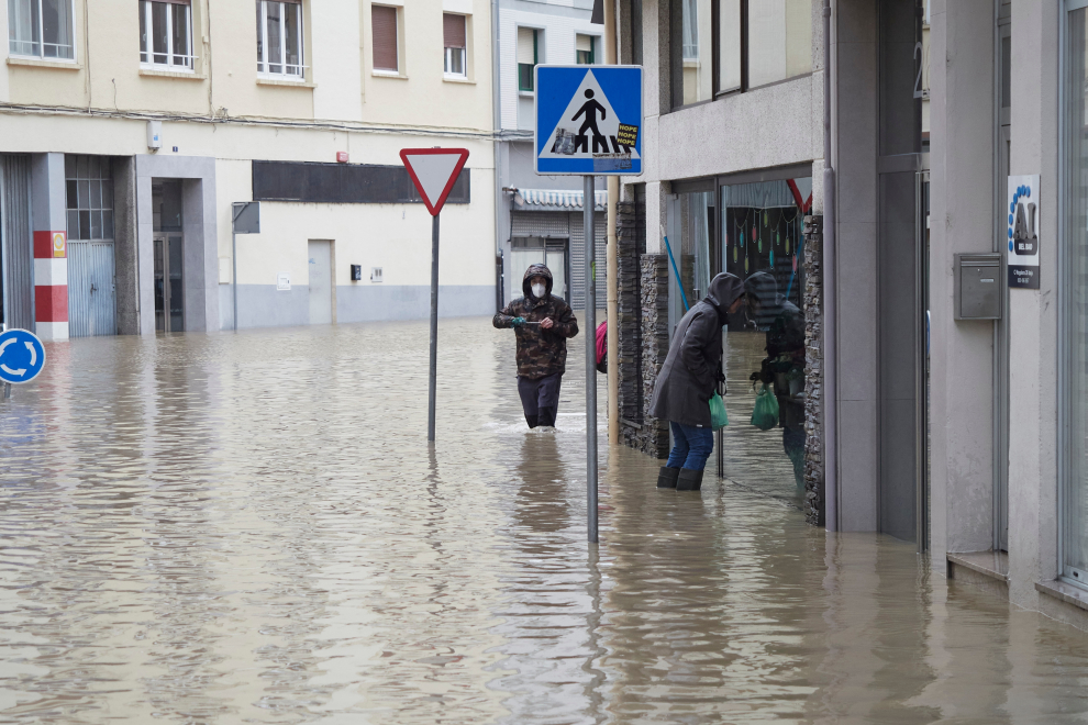 Dos personas caminan por una zona inundada de Burlada, en Pamplona, Navarra.