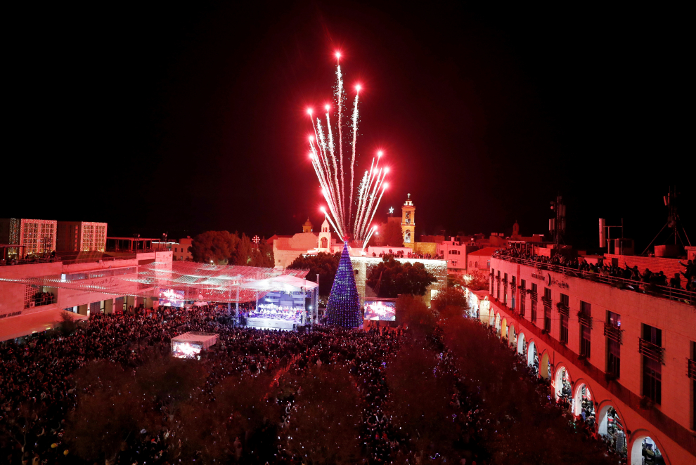 Fuegos artificiales iluminan el cielo sobre la Iglesia de la Natividad en la Plaza del Pesebre en la ciudad cisjordana de Belén durante el encendido del árbol de Navidad.
