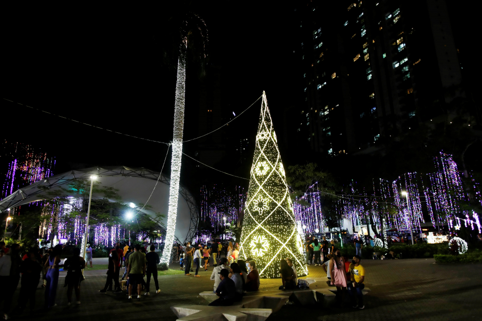 Varias personas observan la exhibición de luces y decoración navideña en el parque Urracá, en Ciudad de Panamá.