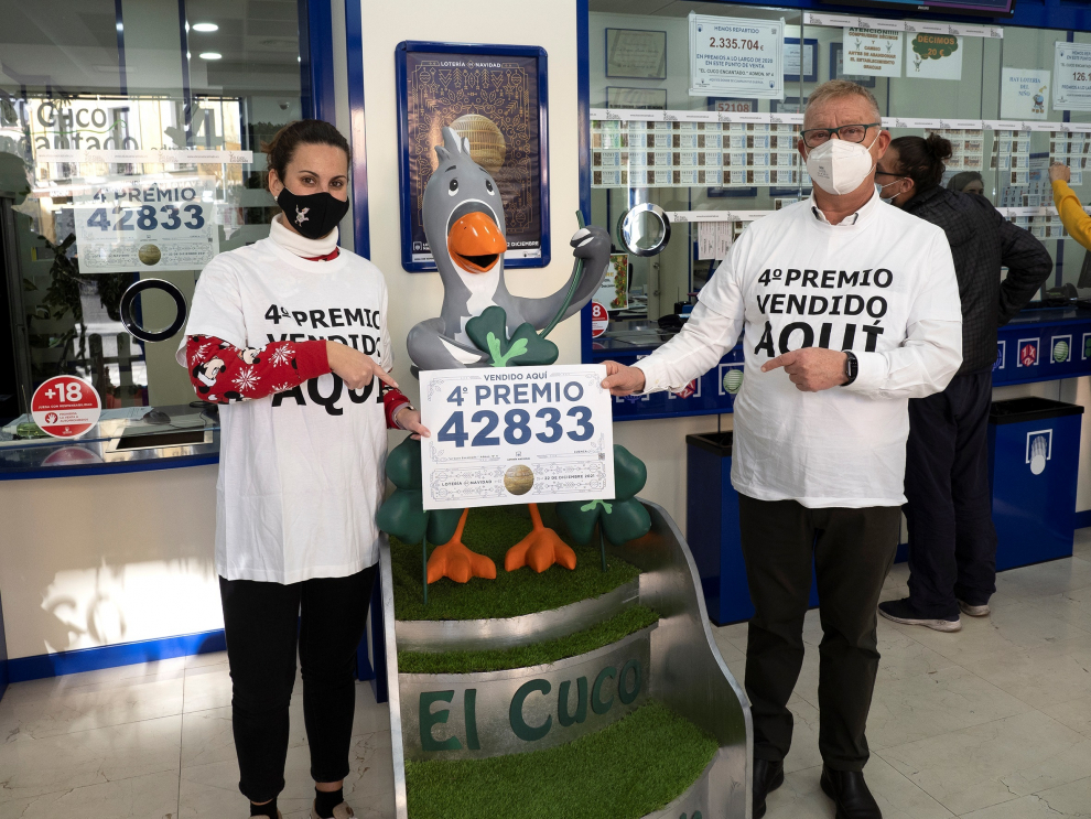Trabajadores de la administración nº 4 de Cuenca, "El Cuco Encantado" muestran el cartel de venta del número 42.833 de la lotería que ha sido agraciado con el primero de los cuartos premios, dotado con 200.000 euros a la serie, 20.000 euros al décimo.