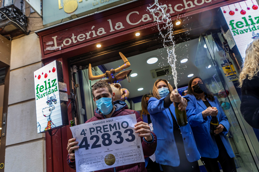 Trabajadores de la administración "La Caprichosa" de Toledo muestran el cartel de venta del número 42.833 de la lotería.