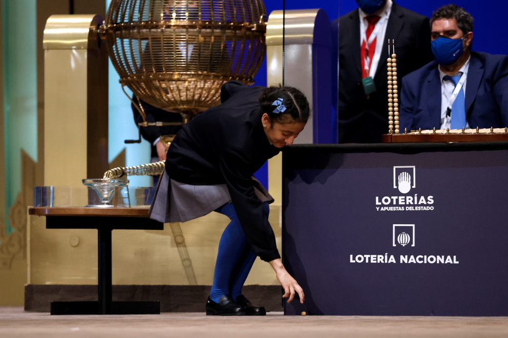Una niña del Colegio de San Ildefonso recoge la bola del primer premio al 86148 del sorteo de la Lotería de Navidad celebrado en el Teatro Real de Madrid.