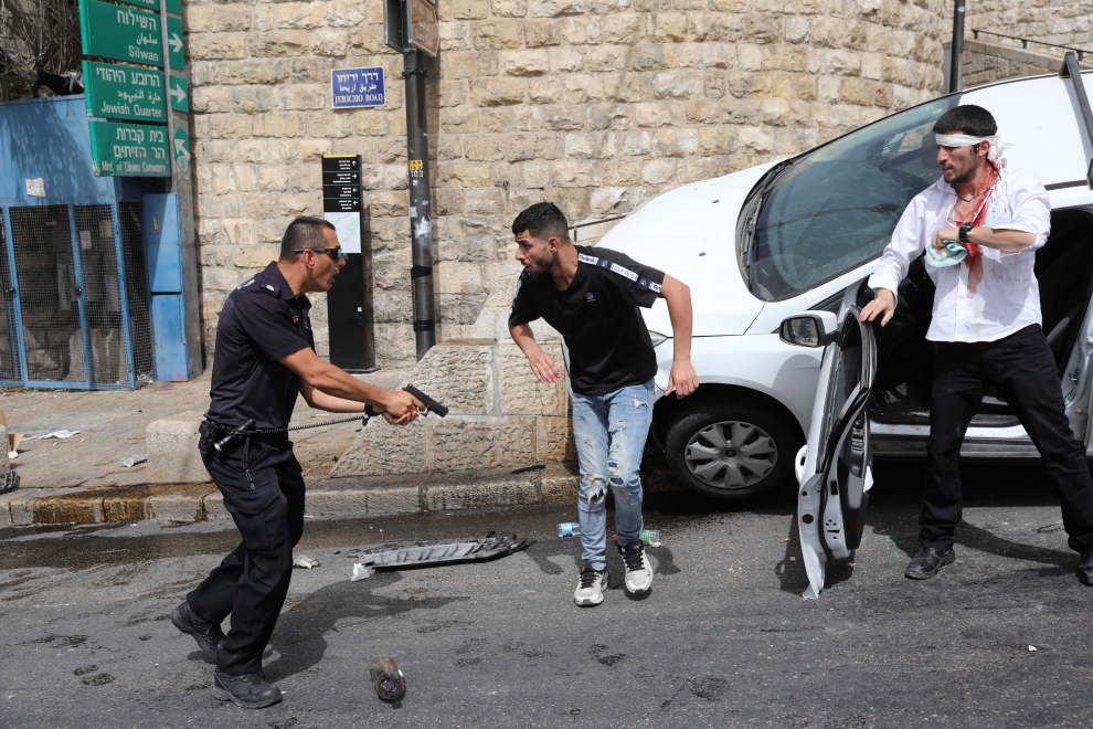 Un policía israelí apunta a un palestino con un arma junto a un judío ultraortodoxo herido que chocó su vehículo cerca de la Puerta de los Leones en Jerusalén, Israel, el 10 de mayo de 2021. En mayo se extendieron las protestas diarias contra el desalojo de familias palestinas del cercano y estratégico barrio de Seij Yarrah, en la zona oriental.