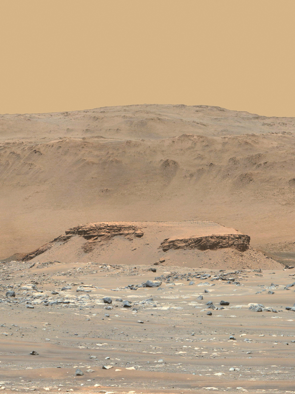Esta imagen en color mejorada del cráter Jezero de Marte fue tomada por el instrumento Mastcam-Z. La colina de primer plano, llamada "Kodiak", está a 2,2 kilómetros del Rover. Las capas de rocas antiguas indican la deposición gradual de sedimentos en el delta de un río seguida de inundaciones.