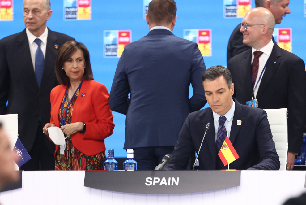 El presidente del Gobierno, Pedro Sánchez, prepara su discurso inaugural de la Cumbre de la OTAN bajo la atenta mirada de Margarita Robles mientras la bandera de España está colocada al revés.