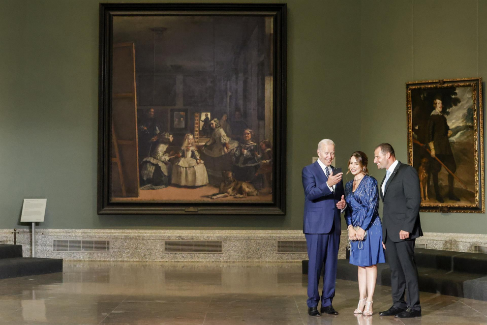 El presidente de los Estados Unidos, Joe Biden (i), enseña su teléfono a la primera ministro de Nueva Zelanda, Jacinda Arderna, delante de el cuadro de Las Meninas.