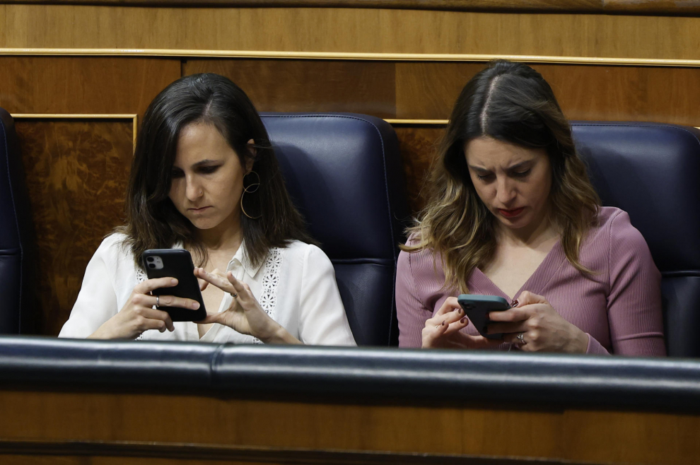 Las ministras de Derechos Sociales, Ione Belarra (i), y de Igualdad, Irene Montero, revisan sus teléfonos durante el debate de la moción de censura de Vox contra el presidente del Gobierno, Pedro Sánchez