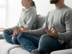 Una pareja practicando ejercicios de relajación y meditación en casa.