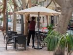 n camarero coloca una sombrilla en la terraza de un bar en la calle Betenchourt Alfonso de Santa Cruz de Tenerife.