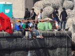 Varios inmigrantes magrebíes este jueves en el muelle de Arguineguín, en el que bajan las garrafas de agua hasta el mar con una cuerda para mantenerlas frescas.