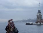 Dos mujeres con mascarilla pasean ante la Torre de la Doncella en Estambul