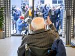 Un anciano saluda a los medios que se agolpan en la puerta para captar la vacunación