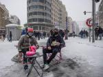 Dos personas se sientan en una nevada Plaza de Callao de Madrid tras el paso de Filomena