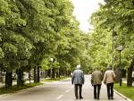 Tres jubilados o pensionistas caminan por un parque